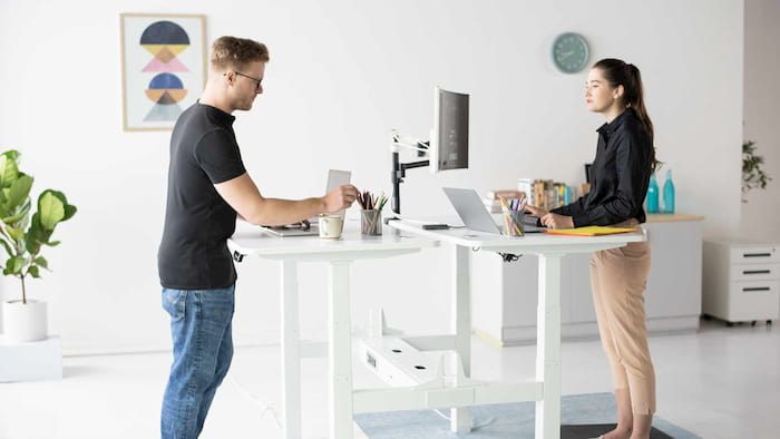 a girl and a man working on a modern white standing desks