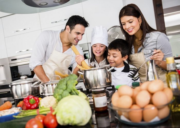 picture of mother, father and one little girl and little boy as a family cooking pasta and a lot of vegetable and eggs in the kitchen