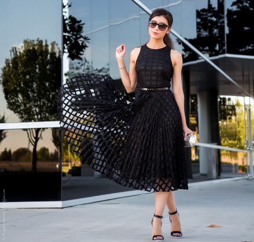picture of a woman in a black midi dress in front a  glass building 