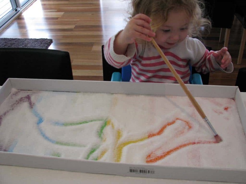 child drawing in salt tray