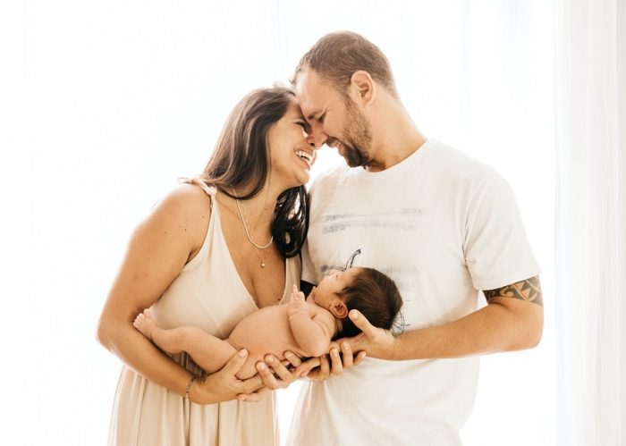 picture of a new parents smiling and holding a naked baby