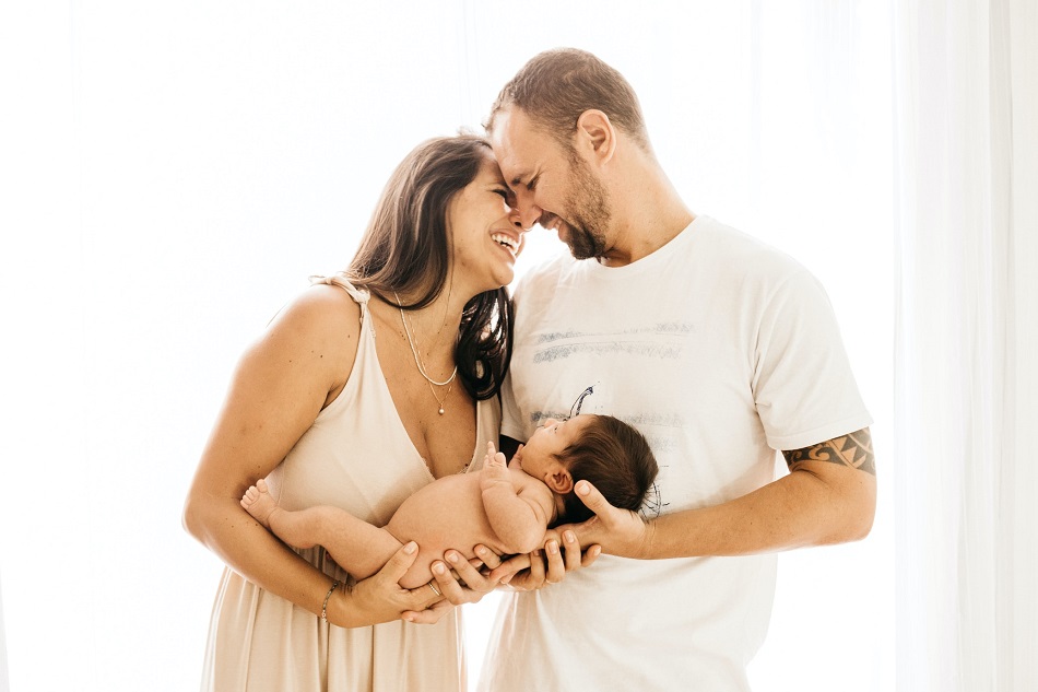 picture of a new parents smiling and holding a naked baby