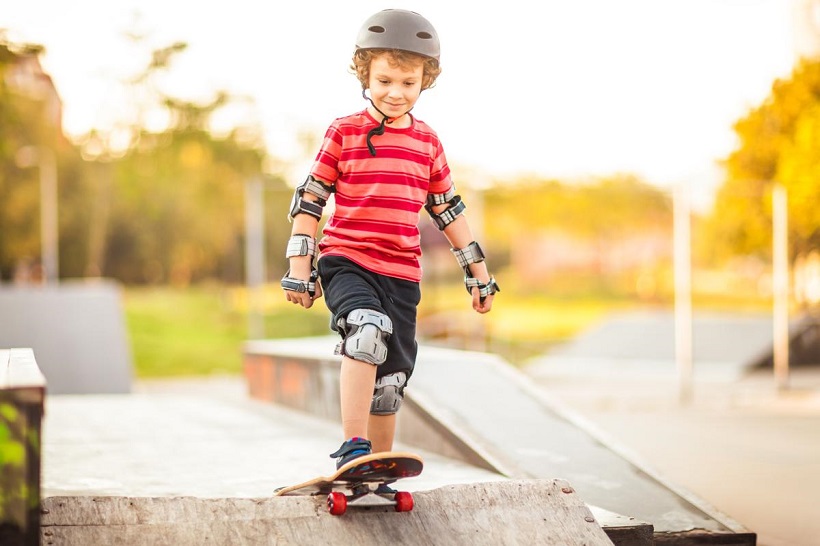picture of a kid skateboarding in a park with safety gear