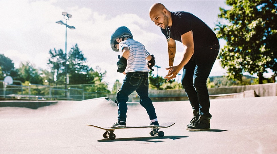 picture of a man beside a kid on skateboard with safety gear