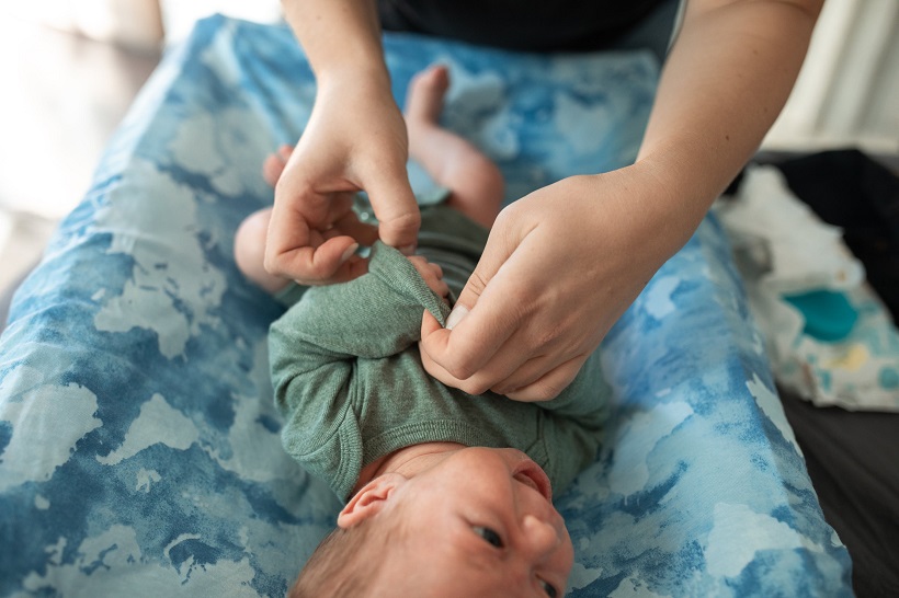 picture of a woman putting clothes on a baby on a changing mat 
