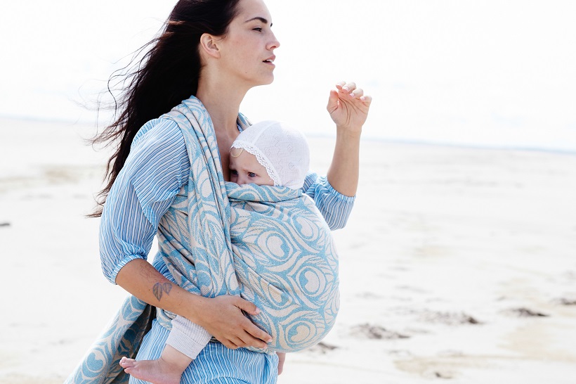 picture of a woman on the beach walking with a baby in a baby carrier wrap