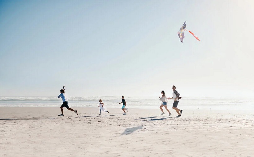 family flying a kite on the beach