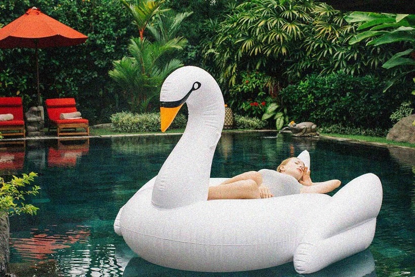 girl floating on an inflatable swan in a pool